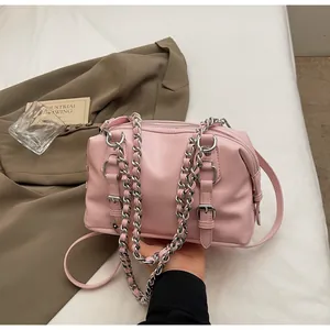 Detailed view of pink crossbody bag with silver chain handle and decorative straps