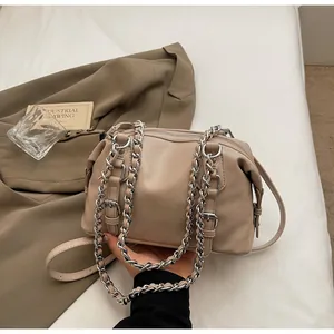 Detail shot of beige faux leather handbag with chunky silver chain and fine buckle strap
