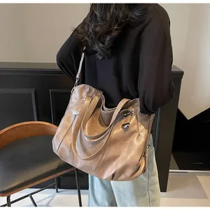 Macro shot of large vintage brown leather tote bag with silver rivets on model shoulder