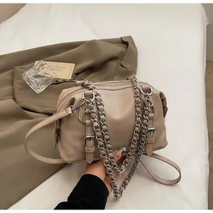 Detail of beige crossbody bag with silver chain handle and decorative straps