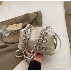 Detail of beige leather handbag with chunky silver chain strap and buckle accents