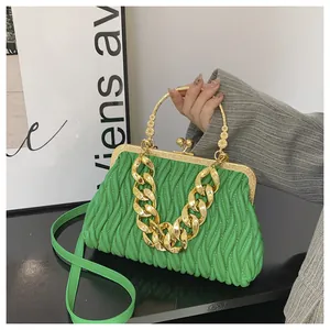 Detail van groene geplooide handtas met vintage metalen sluiting en gouden ketting