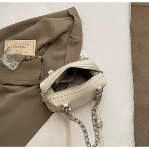 Detail view of beige Boston bag with silver chain strap and multiple interior compartments