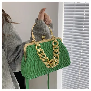 Detail van groene geplooide handtas met gouden ketting en vintage metalen ringgreep