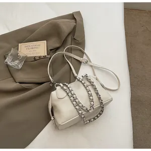 Close-up of beige leather bag with silver chain and side tassel in aesthetic setting