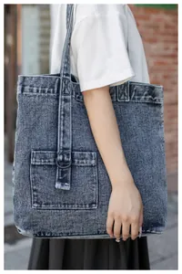 Detail der graublauen Denim-Tragetasche mit Vordertasche, D-Ring und Gurtverzierung