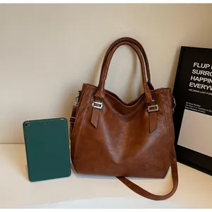 Close-up of brown PU leather tote bag with silver hardware on a minimalist background