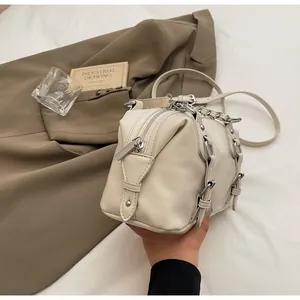 Detail of cream crossbody bag with silver hardware, chains and adjustable buckles