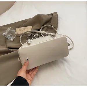 Detail view of cream-colored PU leather bag with silver chain and sleek rectangular base