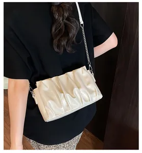 Close-up of pleated cream white crossbody bag with silver chain strap and shiny PU finish