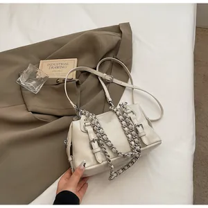 Detail of off-white lychee texture crossbody bag with chunky metal chains and buckles