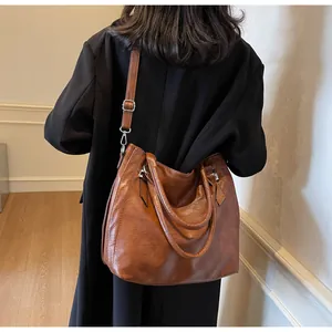 Detail view of large brown retro faux leather tote bag with silver hardware and shoulder strap