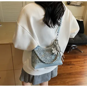 Detail of light blue denim crossbody bag with rhinestone quilting and metal chain handle