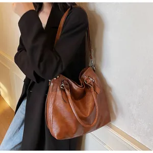 Detail showing the vintage brown faux leather texture and silver hardware of the tote bag