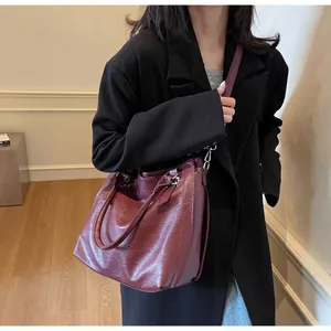 Detailed view of deep red tote bag with leather texture and silver hardware