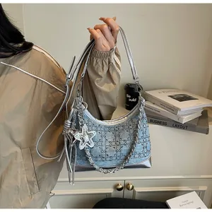 Detail of denim shoulder bag featuring silver sequins, metallic chain and star charms