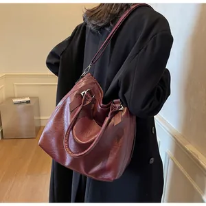 Close-up of wine red lychee pattern leather tote bag carried by model in black coat