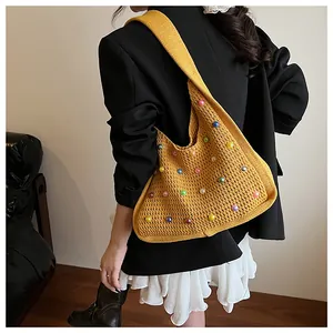 Detail of mustard yellow knit hobo bag with colorful beads worn by a model