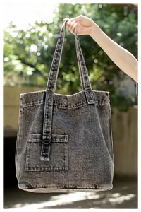 Detailansicht der schwarzen Denim-Tasche mit Vordertasche und dekorativer Metallschnalle