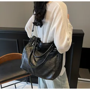 Detail of a black pleated tote bag showing the texture, handles, and detachable shoulder strap