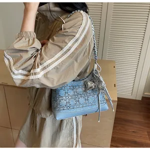 Detail of light blue denim crossbody bag featuring silver chain and sparkling star charms