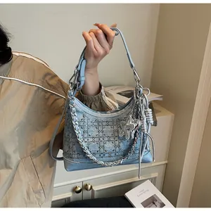 Detail of light blue denim hobo bag with rhinestone pattern and metal chain strap