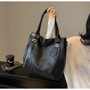Detail of vintage black tote bag with wrinkled leather texture and silver buckle accents