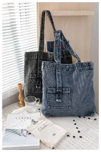 Detail von gewaschenen Denim-Tragetaschen mit Metallringen und Fronttaschen im weichen Licht