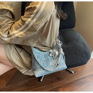 Close-up of light blue denim tote bag with rhinestone studs and silver chain charms