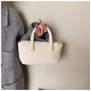 Gros plan du sac cabas crème avec texture tressée et doubles poignées au style épuré