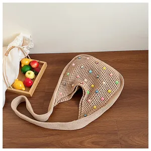 Close-up of a hand-woven tote bag with colorful pearl accents on a wooden table