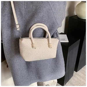 Sac fourre-tout crème chic avec texture tissée porté sur un manteau en laine grise