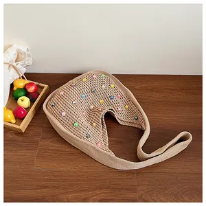 Detail view of hand-woven hobo bag with colorful pearls on a wooden floor