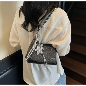 Detail of tweed crossbody bag with silver star charm and chain strap on model