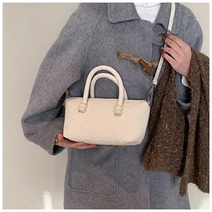 Détail du sac bandoulière crème avec poignée ronde et finition tissée élégante