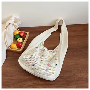Detail of cream knit tote bag with colorful beads on minimalist wooden table