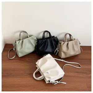 Group shot of pleated crossbody bags in green, black, brown, and cream with dual handles