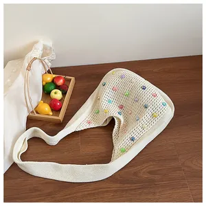 Detail of cream crochet tote bag with colorful beads on a rustic wooden background