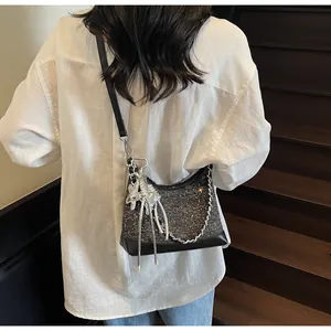 Detail of grey sequin tweed crossbody bag with silver chain and metal charm on shoulder