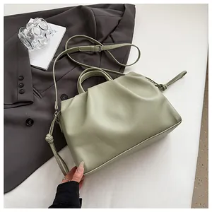 Detail of light green pleated crossbody bag with pebble grain faux leather and silver buckles