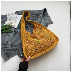 Detail view of ginger yellow knit tote bag featuring colorful faux pearl embellishments