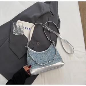 Detail of blue denim crescent bag featuring silver sequin grid and metallic leather trim