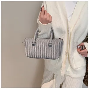 Détail du sac cabas gris avec texture tressée et poignées cylindriques pour femme