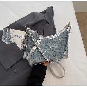 Close-up of denim shoulder bag with rhinestone geometric patterns and silver chain details