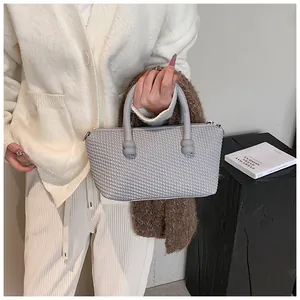 Détail du sac à main gris au tissage bouffant avec anses tubes et nœud décoratif