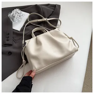 Detail of cream ruched leather crossbody bag with knot shoulder strap and pebble texture