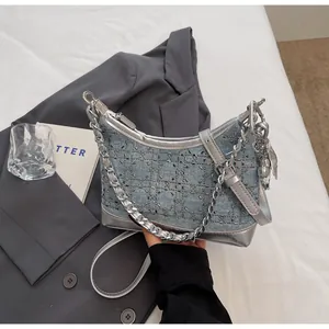 Detail of denim crossbody bag with silver rhinestones, chain and heart charm