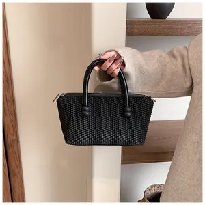 Détail du sac trapèze noir montrant la texture tissée 3D et les poignées cylindriques