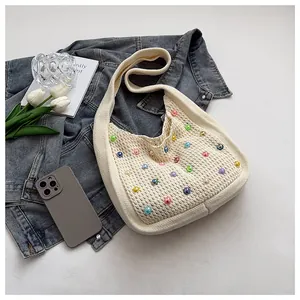 Detail of cream knit tote bag featuring colorful faux pearl beads and soft crochet texture