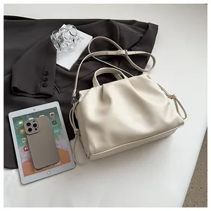 Close-up of cream pleated shoulder bag with lychee texture and decorative knot detail